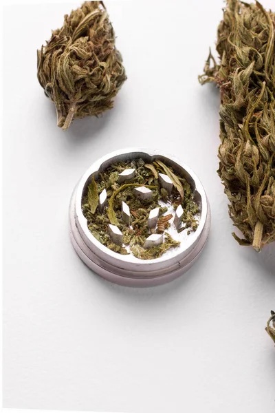 Coni di marijuana accanto a un macinino su uno spazio di copia di sfondo bianco — Foto Stock