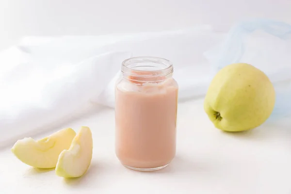 Puré de manzana en un frasco sobre un fondo blanco junto a los ingredientes para cocinar en casa. espacio de copia — Foto de Stock