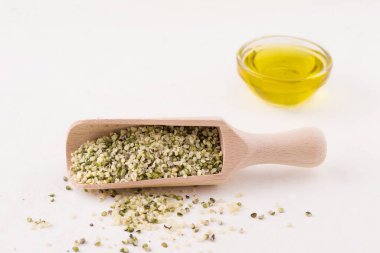 Ahşap bir kepçeyle beyaz arka planda soyulmuş kenevir tohumları. Boşluğu kopyala