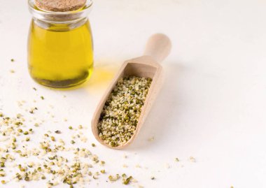 Beyaz arka planda bir kepçe tahtanın içindeki soyulmuş kenevir tohumları. Boşluğu kopyala