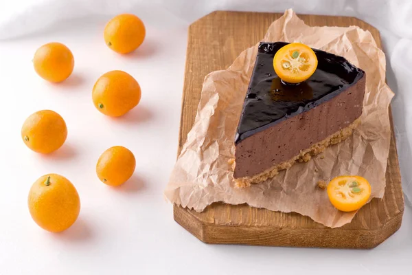 Bolo de chocolate decorado com fatias de kumquat em um prato branco ao lado de uma fruta cítrica inteira — Fotografia de Stock