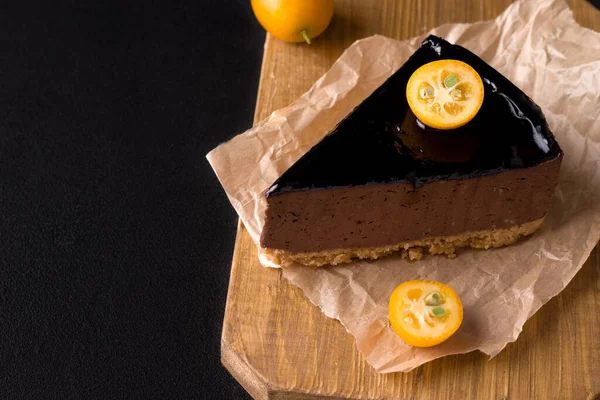 Bolo de chocolate doce decorado com kumquat em um fundo preto. espaço de cópia — Fotografia de Stock