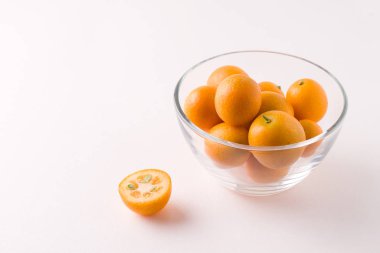 Beyaz arka planda cam bir kasede tropik kumkat meyvesi. Boşluğu kopyala