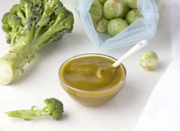 Baby puree in een glazen schaal van spruitjes en broccoli naast verse ingrediënten — Stockfoto