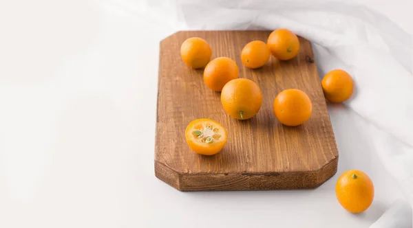 Tropische Zitrusfrüchte Kumquat auf einem Holzbrett auf weißem Hintergrund. Kopierraum — Stockfoto