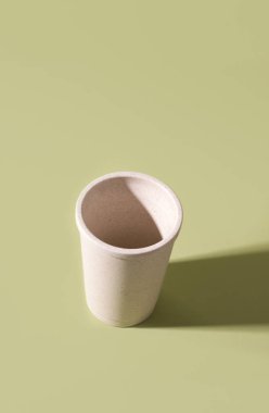 Yeşil zemin üzerinde boş samandan yapılmış yeniden kullanılabilir bardak. Boşluğu kopyala