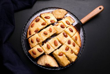 Siyah arkaplanda kesilen irmikli ve bademli Basbus Arap turtası.