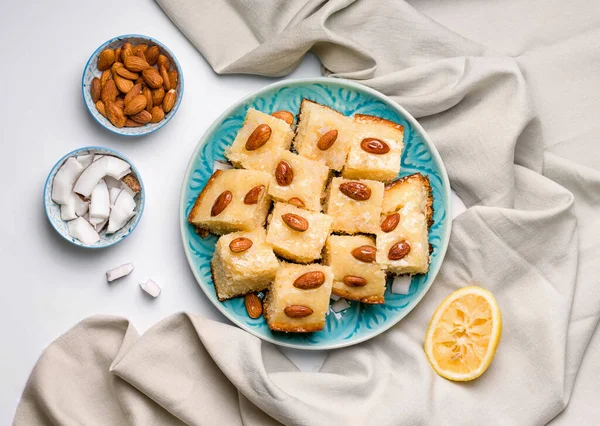 oriental dish sweet cake with semolina, coconut and almonds on a blue plate on a light background