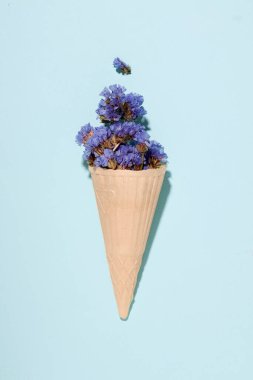 Yaz konsepti. Dondurmalı waffle fincanı, mavi arka planda çiçekler.