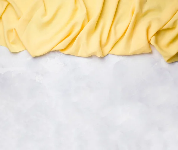 yellow fabric falling down from above on a concrete white background. copy space