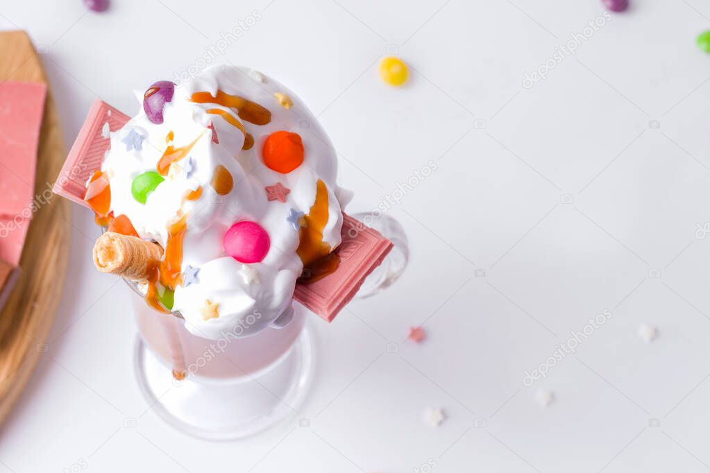 Caramel dessert with cream decorated with sweets on a white background. copy space