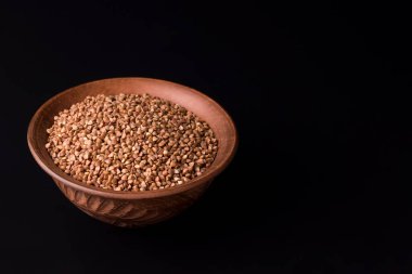 Siyah arka planda, kil bir kasede karabuğday. Boşluğu kopyala