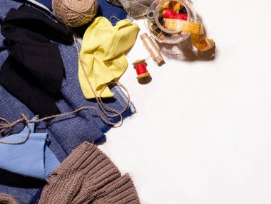 Beyaz bir masa üzerindeki ipliklerin ve düğmelerin yanında farklı renkte kumaş parçaları. boro dikiş konsepti