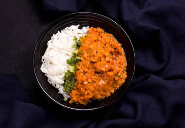 Dhal Hint kırmızı mercimek çorbası ve bir tabak pilav. Siyah arka planda, mavi keten kumaşın yanında. Geleneksel mutfak