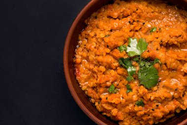 Siyah arka planda kişniş soslu geleneksel vejetaryen kırmızı mercimek çorbası. Boşluğu kopyala