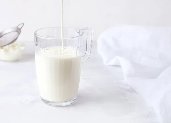 Gefermenteerde melk drank kefir wordt gegoten in een glas op een witte achtergrond. — Stockfoto