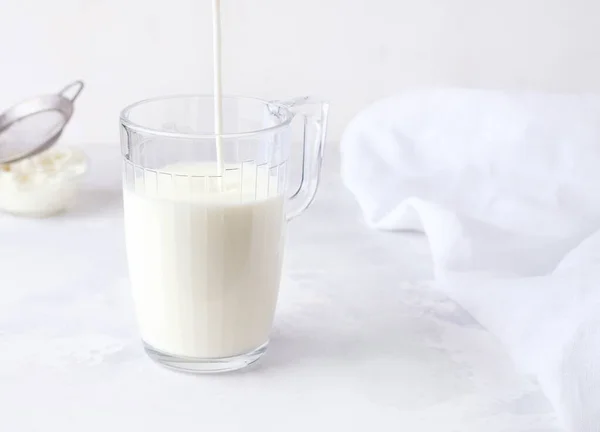 Fermente edilmiş süt kefir beyaz arka planda bir bardağa dökülür..
