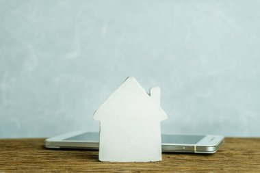 Domuzcuk bankasının ahşap evini izole edilmiş siyah akıllı telefon ekranında, anahtar ve madeni paralar yığını akıllı ev uzaktan kontrol sistemi için internet dijital banka kredi sigortası mobil uygulamadan konut kredisi finansmanı için kurtarıyorum