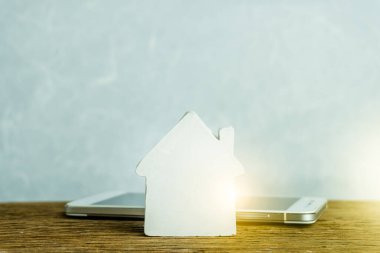 Domuzcuk bankasının ahşap evini izole edilmiş siyah akıllı telefon ekranında, anahtar ve madeni paralar yığını akıllı ev uzaktan kontrol sistemi için internet dijital banka kredi sigortası mobil uygulamadan konut kredisi finansmanı için kurtarıyorum