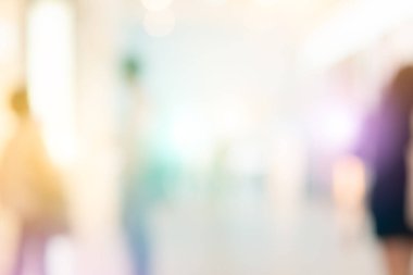 Lüks moda alışveriş merkezlerinde arka planda bokeh ışığı ve mağazaların vitrinlerinde ve mağazaların kadın ve erkek müşterilerinin yürüme koridorlarında yürüdüğü modern modellerin görüntülerinde bulanıklık. 