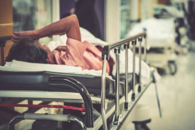 Görüntü hastanesinin arka planında yaşlı bir hasta yatıyor ve tekerlekli sandalye bekleme koridorunda bekliyor. Profesyonel hemşire ve doktorun desteğiyle hasta insanlar için kötü sağlık hizmeti 