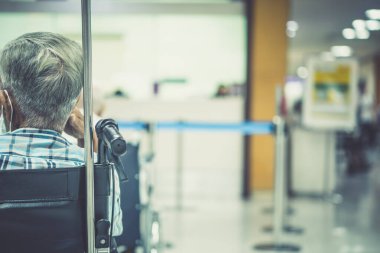Görüntü hastanesinin arka planında yaşlı bir hasta yatıyor ve tekerlekli sandalye bekleme koridorunda bekliyor. Profesyonel hemşire ve doktorun desteğiyle hasta insanlar için kötü sağlık hizmeti 