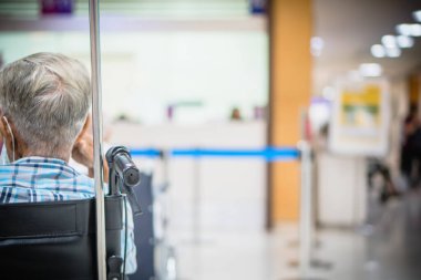 Görüntü hastanesinin arka planında yaşlı bir hasta yatıyor ve tekerlekli sandalye bekleme koridorunda bekliyor. Profesyonel hemşire ve doktorun desteğiyle hasta insanlar için kötü sağlık hizmeti 