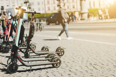 Yazın kaldırımda park etmiş elektrikli scooter 'ı kira için mobil telefon uygulaması kullanarak paylaşmanın arka planı. Avrupa 'daki akıllı kentlerde kullanım ulaşım, trafik ve güvenli çevre kirliliğine yardımcı olmaktadır