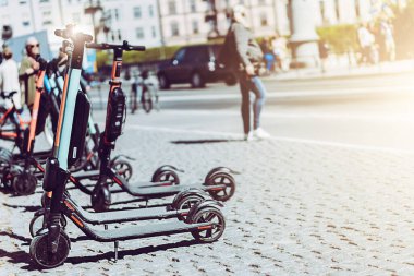 Yazın kaldırımda park etmiş elektrikli scooter 'ı kira için mobil telefon uygulaması kullanarak paylaşmanın arka planı. Avrupa 'daki akıllı kentlerde kullanım ulaşım, trafik ve güvenli çevre kirliliğine yardımcı olmaktadır