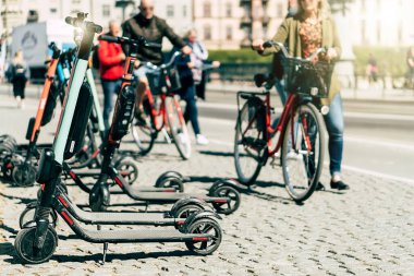 Yazın kaldırımda park etmiş elektrikli scooter 'ı kira için mobil telefon uygulaması kullanarak paylaşmanın arka planı. Avrupa 'daki akıllı kentlerde kullanım ulaşım, trafik ve güvenli çevre kirliliğine yardımcı olmaktadır