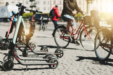 Yazın kaldırımda park etmiş elektrikli scooter 'ı kira için mobil telefon uygulaması kullanarak paylaşmanın arka planı. Avrupa 'daki akıllı kentlerde kullanım ulaşım, trafik ve güvenli çevre kirliliğine yardımcı olmaktadır