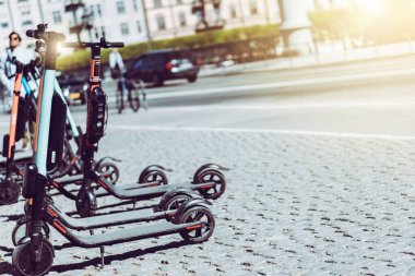 Yazın kaldırımda park etmiş elektrikli scooter 'ı kira için mobil telefon uygulaması kullanarak paylaşmanın arka planı. Avrupa 'daki akıllı kentlerde kullanım ulaşım, trafik ve güvenli çevre kirliliğine yardımcı olmaktadır