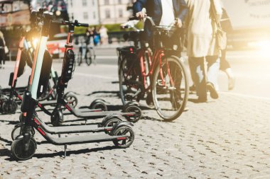 Yazın kaldırımda park etmiş elektrikli scooter 'ı kira için mobil telefon uygulaması kullanarak paylaşmanın arka planı. Avrupa 'daki akıllı kentlerde kullanım ulaşım, trafik ve güvenli çevre kirliliğine yardımcı olmaktadır