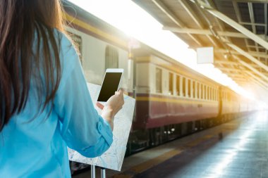 Tren platformundaki genç sırt çantalı turist internetteki wi-fi arama kılavuzu bilgilerini kullanıyor ucuz indirimli tanıtım kitabı otobüs otobüs bileti Coronavirus karantinasından sonra otel uçuşu