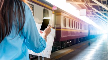 Tren platformundaki genç sırt çantalı turist internetteki wi-fi arama kılavuzu bilgilerini kullanıyor ucuz indirimli tanıtım kitabı otobüs otobüs bileti Coronavirus karantinasından sonra otel uçuşu