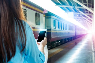 Tren platformundaki genç sırt çantalı turist internetteki wi-fi arama kılavuzu bilgilerini kullanıyor ucuz indirimli tanıtım kitabı otobüs otobüs bileti Coronavirus karantinasından sonra otel uçuşu