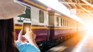 Tren platformundaki genç sırt çantalı turist internetteki wi-fi arama kılavuzu bilgilerini kullanıyor ucuz indirimli tanıtım kitabı otobüs otobüs bileti Coronavirus karantinasından sonra otel uçuşu