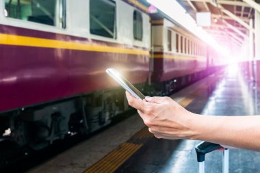 Tren platformundaki genç sırt çantalı turist internetteki wi-fi arama kılavuzu bilgilerini kullanıyor ucuz indirimli tanıtım kitabı otobüs otobüs bileti Coronavirus karantinasından sonra otel uçuşu