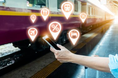 Tren platformundaki genç sırt çantalı turist internetteki wi-fi arama kılavuzu bilgilerini kullanıyor ucuz indirimli tanıtım kitabı otobüs otobüs bileti Coronavirus karantinasından sonra otel uçuşu