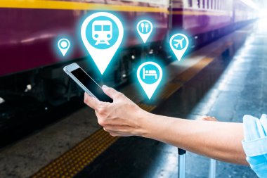 Tren platformundaki genç sırt çantalı turist internetteki wi-fi arama kılavuzu bilgilerini kullanıyor ucuz indirimli tanıtım kitabı otobüs otobüs bileti Coronavirus karantinasından sonra otel uçuşu