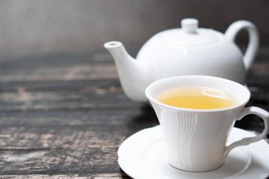 Lezzetli organik sağlıklı bitkisel sarı çay seti. Temiz beyaz seramik klasik bardak ve demlik. Eski doğal ahşap masa otantik ev yapımı egzotik çay seti.