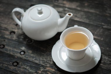 Lezzetli organik sağlıklı bitkisel sarı çay seti. Temiz beyaz seramik klasik bardak ve demlik. Eski doğal ahşap masa otantik ev yapımı egzotik çay seti.