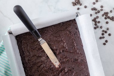 Keto çikolatalı kek hamuru metal fırın tavasında parşömen kağıdı ve tavada set dışı uzay boşluğu ile kaplı.