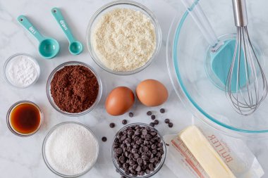 Keto çikolatalı brownie malzemeleri ve aletler, yukarıdan hafif arka planda çekilmiş.