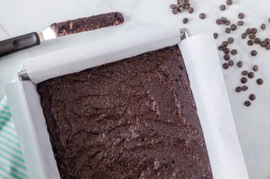 Keto çikolatalı browni hamuru metal fırın tavasında parşömen kağıdı ve set dışı uzay boşluğuyla kaplı.