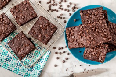 Keto çikolatalı brovnileri kapatın. Parlak mavi tabakta oturuyorlar. Ekstra brovniler de çiçek peçetesiyle fırında.