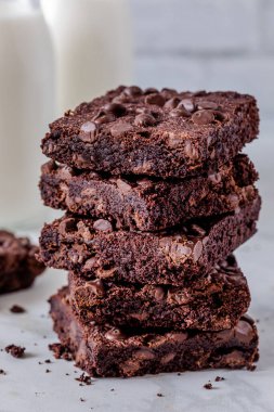 Beyaz tuğla duvara karşı iki şişe sütle çikolata parçalı browni yığınını kapat.