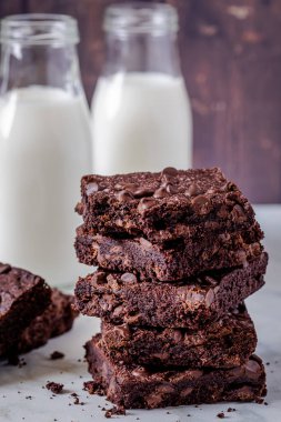 Kestaneli çikolatalı browni yığınını kapat. Birinden bir ısırık al, iki şişe sütle birlikte koyu ahşap duvara yapıştır.