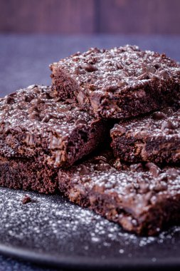 Kestane çikolatalı kek yığını koyu ahşap arka plana pudra şekeri serpiştirilmiş.