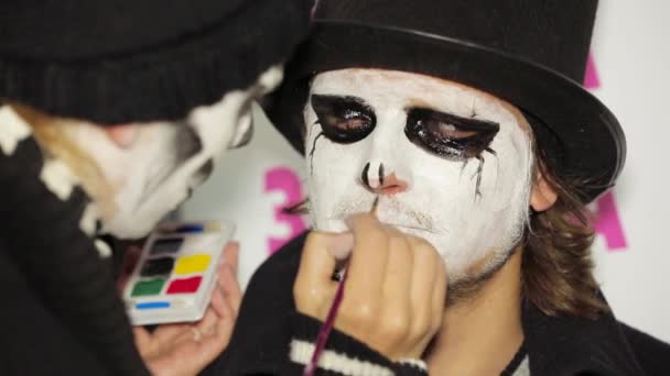 Jovem mulher aplicando maquiagem escura no rosto de Mans no Halloween — Vídeo de Stock